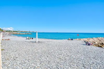 a group of people sitting on a rocky beach at Studio de la plage - Mer, Terrasse et garage in Cagnes-sur-Mer