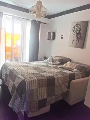 a bedroom with a bed with a blanket and a window at CHAMBRE CHEZ L'HABITANT - ROOM IN THE OWNER'S APARTMENT in Nice