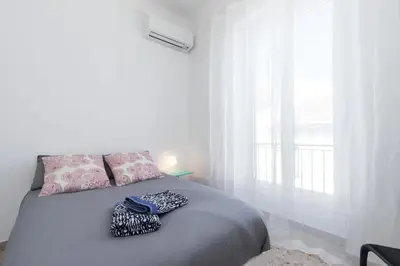 a white bedroom with a bed with a window at FEEL HOME - ASSALIT in Nice
