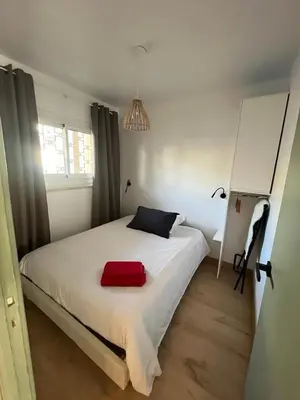 a bedroom with a white bed with a red bag on it at 3 Piéces confort climatisé vue mer, 4 personnes à Saint-Jean Cap Ferrat à proximité de monaco et menton in Saint-Jean-Cap-Ferrat