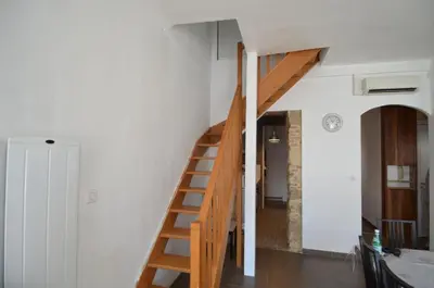 a wooden staircase in a room with white walls at DUPLEX BORRIGLIONE - Spacieux appartement pour 6 personnes au pied du tram in Nice
