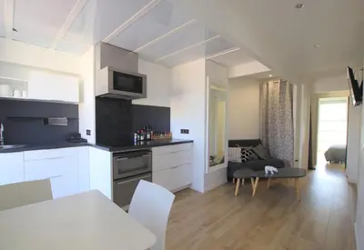 a kitchen and living room with white cabinets and a table at La terrasse de Carras in Nice