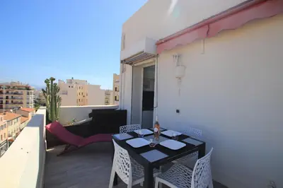 a balcony with a black table and chairs and a couch at La terrasse de Carras in Nice