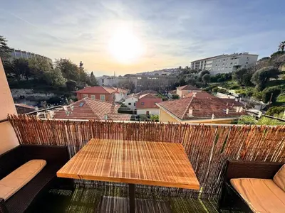 a wooden table on a balcony with a view of a city at Spacieux/paisible 5 pièces en plein coeur de Nice in Nice