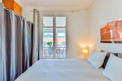a bedroom with a white bed and a window at La terrasse de Rossini in Nice