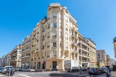 a tall white building on a city street with cars at La terrasse de Rossini in Nice