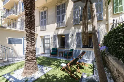 a patio with chairs and palm trees in front of a building at Luxury 3 Bdr Garden & Parking - Angels' Garden in Nice