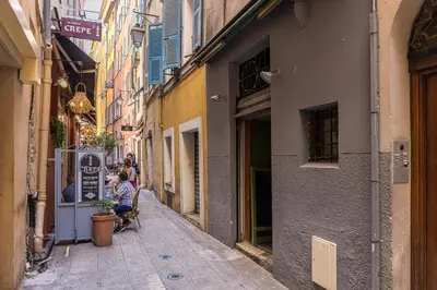a narrow alleyway with people sitting in chairs on a street at Bright 1 Bdr in the Old Town in Nice
