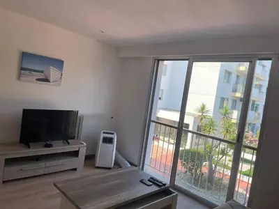 a living room with a television and a large sliding glass door at Studio bord de mer in Saint-Laurent-du-Var