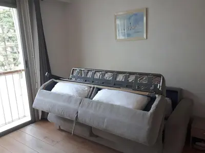 a couch with pillows in a room with a window at Studio bord de mer in Saint-Laurent-du-Var