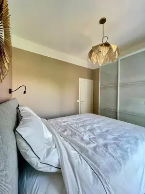 a bedroom with a large white bed with a chandelier at Air-conditioned apartment with garage near the sea in Nice