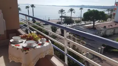 a table on a balcony with a view of the ocean at La Plage in Cagnes-sur-Mer