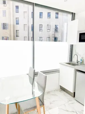a white table and chairs in a room with a window at Halévy Résidence in Nice
