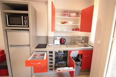 a small kitchen with red cabinets and a refrigerator at Red studio Buffa in Nice