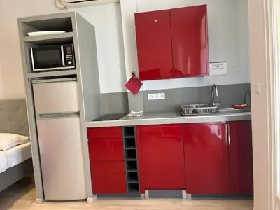 a small kitchen with red cabinets and a refrigerator at Red studio Buffa in Nice