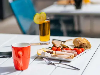 a cafeteria with tables and chairs and tables and chairs at ibis Styles Nice Aéroport Arenas in Nice