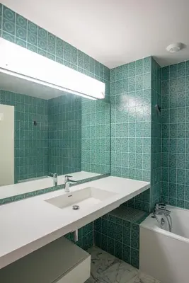 a green tiled bathroom with a sink and a mirror at 3 pièces vue mer et piscine quartier Parc Impérial in Nice