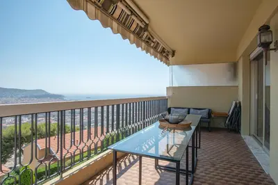 a balcony with a table and a view of the ocean at 3 pièces vue mer et piscine quartier Parc Impérial in Nice