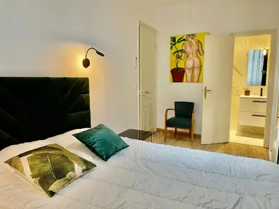 a bedroom with a bed with a green pillow and a chair at Spacious 3 BR flat Nice center - magnificent view in Nice