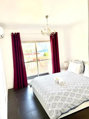 a bedroom with a bed with red curtains and a window at Beaulieu Sur Mer: Superbe Appart avec vue Mer in Beaulieu-sur-Mer