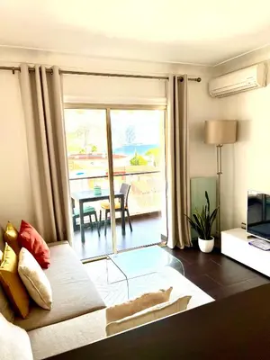 a living room with a couch and a view of a patio at Beaulieu Sur Mer: Superbe Appart avec vue Mer in Beaulieu-sur-Mer