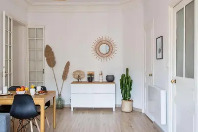 a white living room with a table and a mirror at Appartement Pertinax - Welkeys in Nice