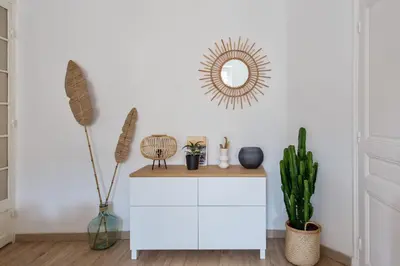 a white cabinet in a room with plants and a mirror at Appartement Pertinax - Welkeys in Nice