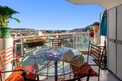 a balcony with a table with an open book on it at La Coquette - Sea View - Parking - AC - Pool in Nice