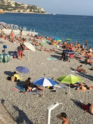 a crowd of people on a beach with umbrellas at La Coquette - Sea View - Parking - AC - Pool in Nice