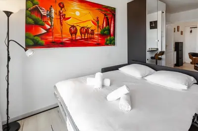 a white bed in a room with a painting on the wall at La Coquette - Sea View - Parking - AC - Pool in Nice