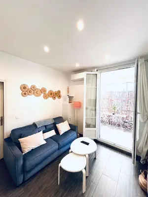 a living room with a blue couch and a table at Studio Cocooning avec terrasse au calme Quartier Les Musiciens Mer à 7 minutes à pieds in Nice