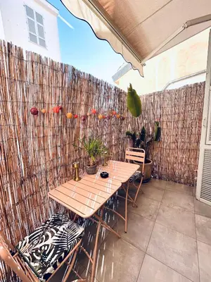 a patio with a wooden table and chairs and a fence at Studio Cocooning avec terrasse au calme Quartier Les Musiciens Mer à 7 minutes à pieds in Nice