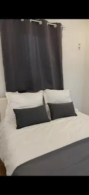 a bed with a black headboard and white pillows at Appartement avec piscine privée in Cagnes-sur-Mer