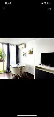 a dining room with a table and chairs and a television at Appartement avec piscine privée in Cagnes-sur-Mer