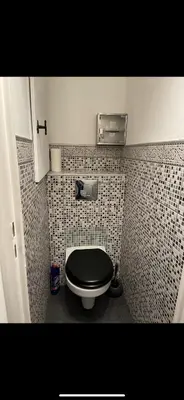a bathroom with a toilet with a black seat at Appartement avec piscine privée in Cagnes-sur-Mer