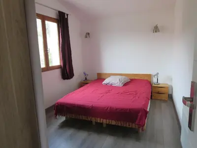 a bedroom with a red bed and a window at 2P entre mer et montagne in Gattières