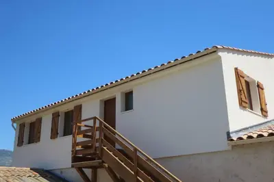 a white house with a wooden staircase in front of it at 2P entre mer et montagne in Gattières