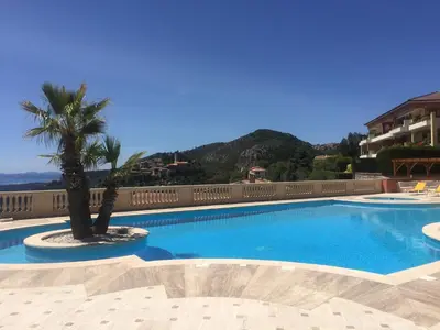 a swimming pool with a palm tree next to a building at Stunning Penthouse with panoramic views of Eze Village and the French Riviera in Èze