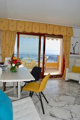 a living room with a table and chairs and the ocean at Stunning Penthouse with panoramic views of Eze Village and the French Riviera in Èze