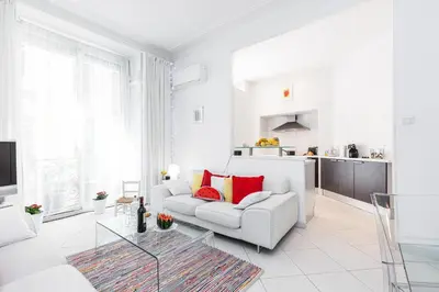 a white living room with a white couch and red pillows at FEEL HOME - GRIMALDI in Nice