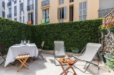 a table and chairs on a patio with a hedge at FEEL HOME - GRIMALDI in Nice