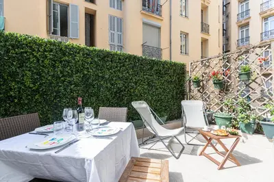 a table with wine glasses and chairs on a patio at FEEL HOME - GRIMALDI in Nice
