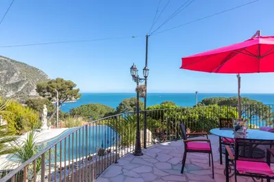 a patio with a table and chairs and an umbrella at Villa Panorama in Èze