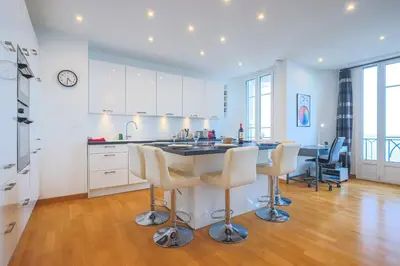 a kitchen with white cabinets and a large island with bar stools at Sea View Large 2 Bdr Promenade des Anglais in Nice