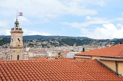 a clock tower with a flag on top of a city at La Providence in Nice