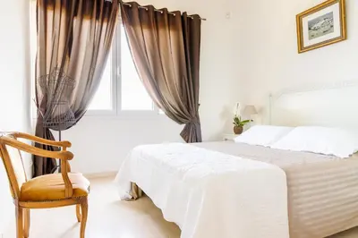 a bedroom with a bed and a chair and a window at Sea View Apartment with Private Secure Parking 1 in Villefranche-sur-Mer