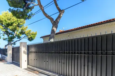a fence in front of a house with trees at Sea View Apartment with Private Secure Parking 1 in Villefranche-sur-Mer