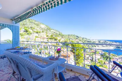 a balcony with a table and chairs and a view of the ocean at Terrace on the Bay 2 Villefranche-sur-Mer, AP4243 by Riviera Holiday Homes in Villefranche-sur-Mer