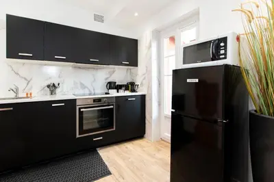 a kitchen with black cabinets and a black refrigerator at Maison Bianchi - Villefranche in Villefranche-sur-Mer
