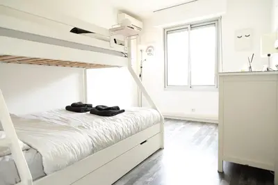 a white bedroom with a bunk bed and a window at Le Syrius in Nice